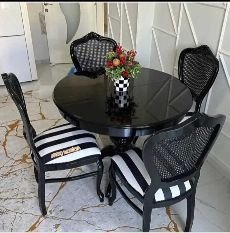 Siyah baba ayak yuvarlak masa ve siyah beyaz çizgili sandalyelerden oluşan şık mutfak yemek takımı